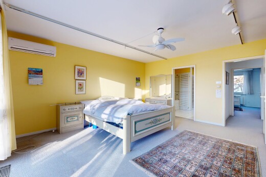 carpeted room featuring track lighting, a wall mounted air conditioner, a ceiling fan, and connected bathroom