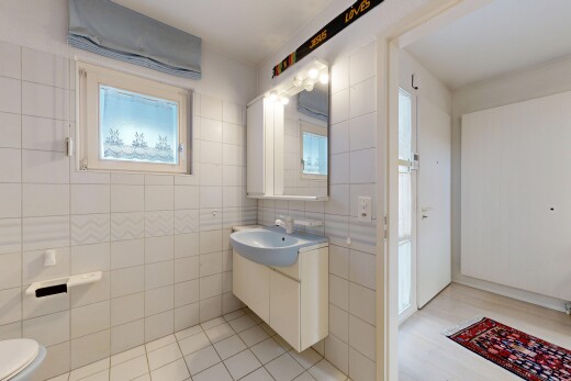 salle de bains avec lavabo (ou coiffeuse selon le contexte), mur en carrelage, tile wall, toilette, et miroir