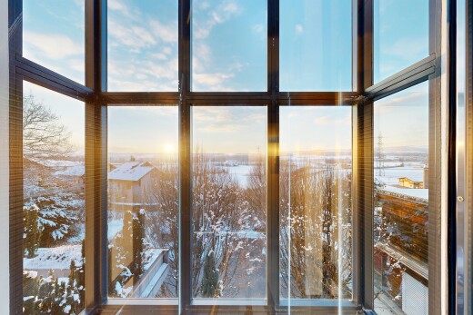 snow covered back of property featuring a sunroom