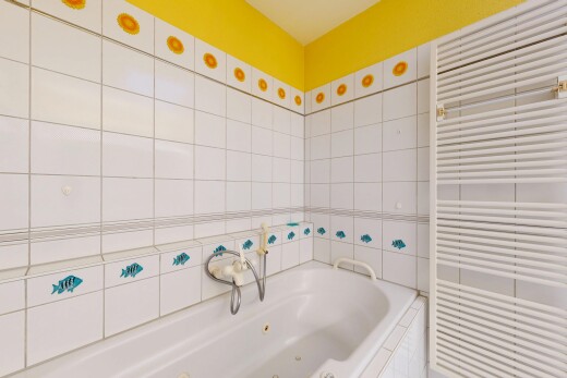 bathroom featuring radiator heating unit, a jetted tub, a towel warming rack, and tile walls