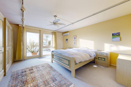 room / bedroom featuring light colored carpet, ceiling fan, and a wall unit AC