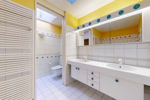 full bath with radiator, double vanity, a skylight, tile walls, and light tile patterned floors