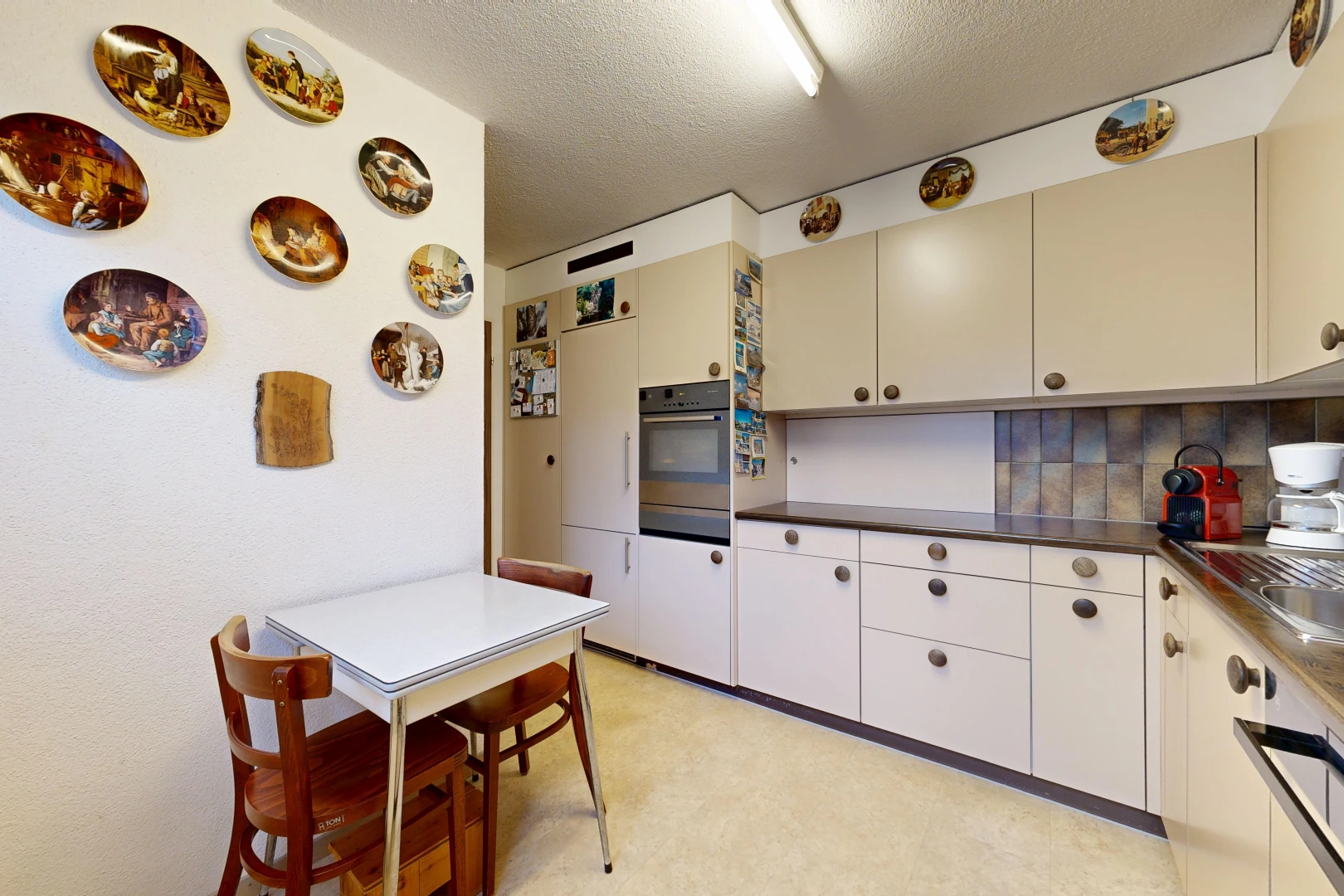 kitchen featuring dark countertops, a textured ceiling, cream cabinetry, and tasteful backsplash