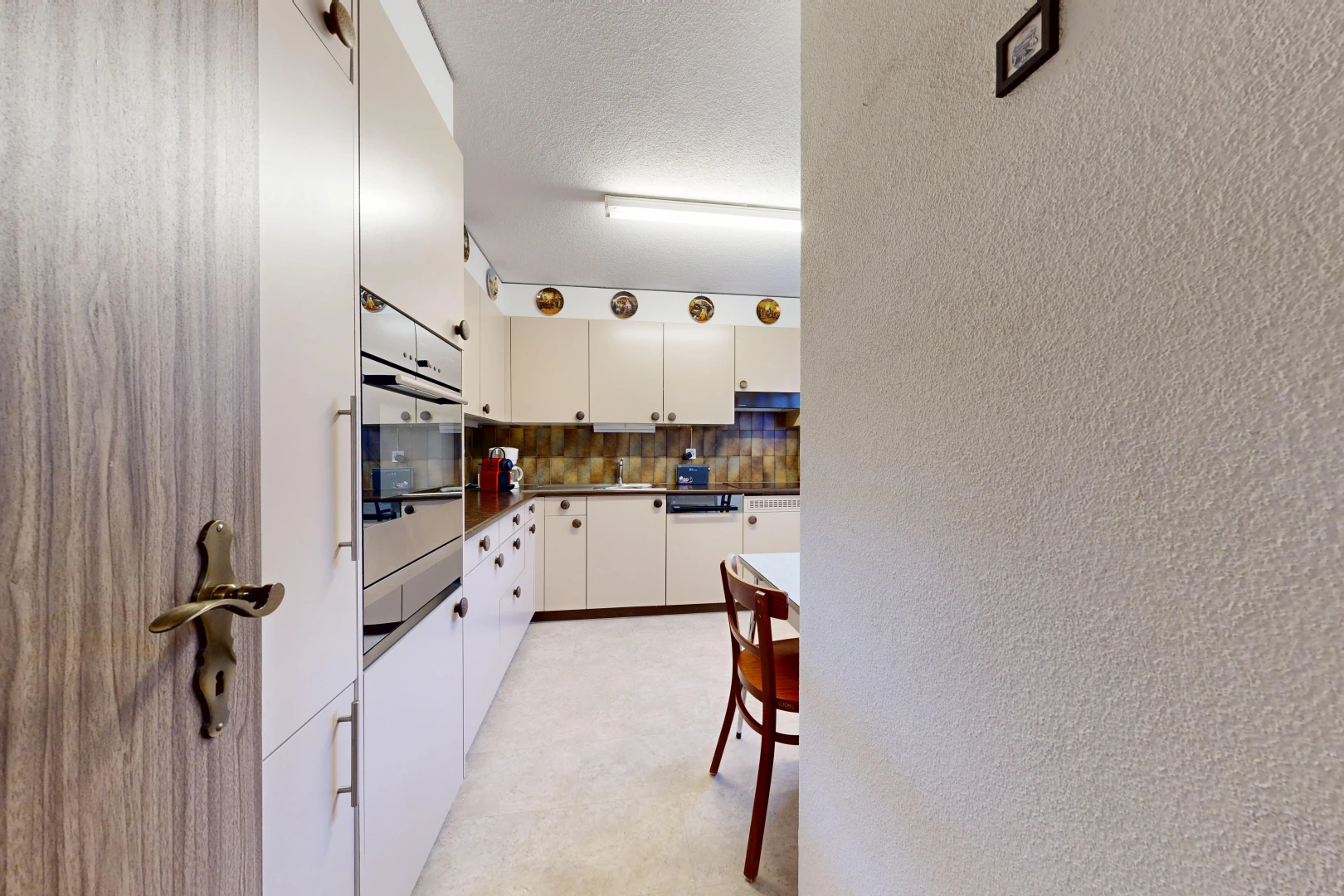 kitchen with dark countertops, a textured wall, stainless steel oven, and decorative backsplash