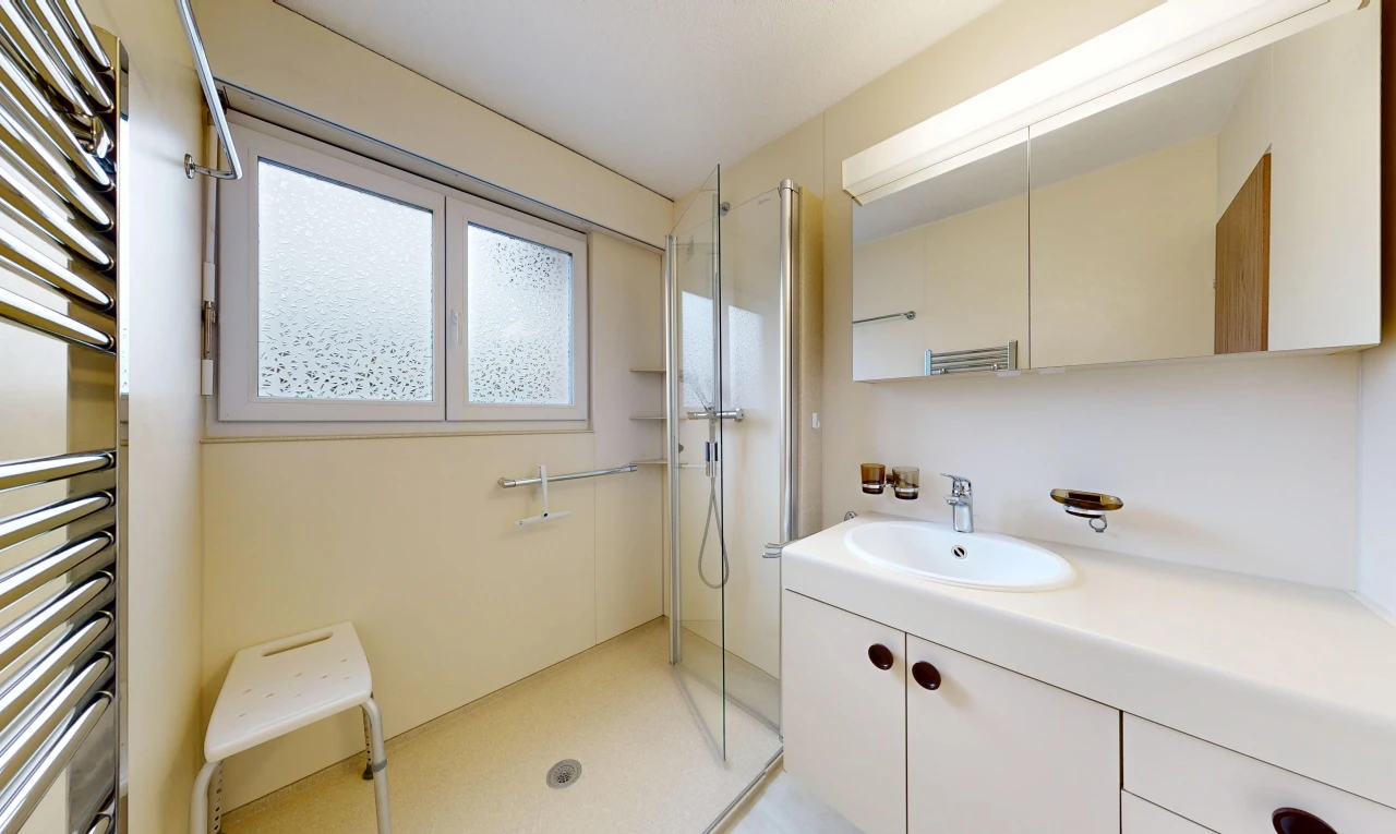 bathroom with a towel warmer, a shower stall, and vanity