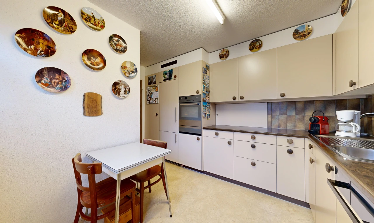 kitchen featuring dark countertops, a textured ceiling, cream cabinetry, and tasteful backsplash