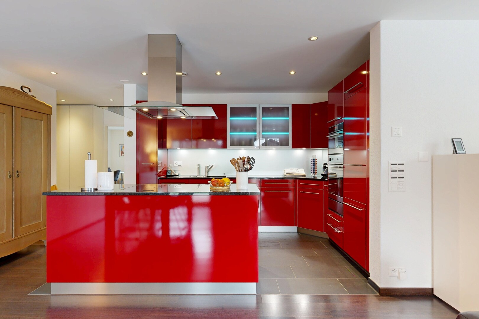 cuisine avec armoires rouges, armoires à panneau plat, hotte, inside property, et armoires avec insert en verre