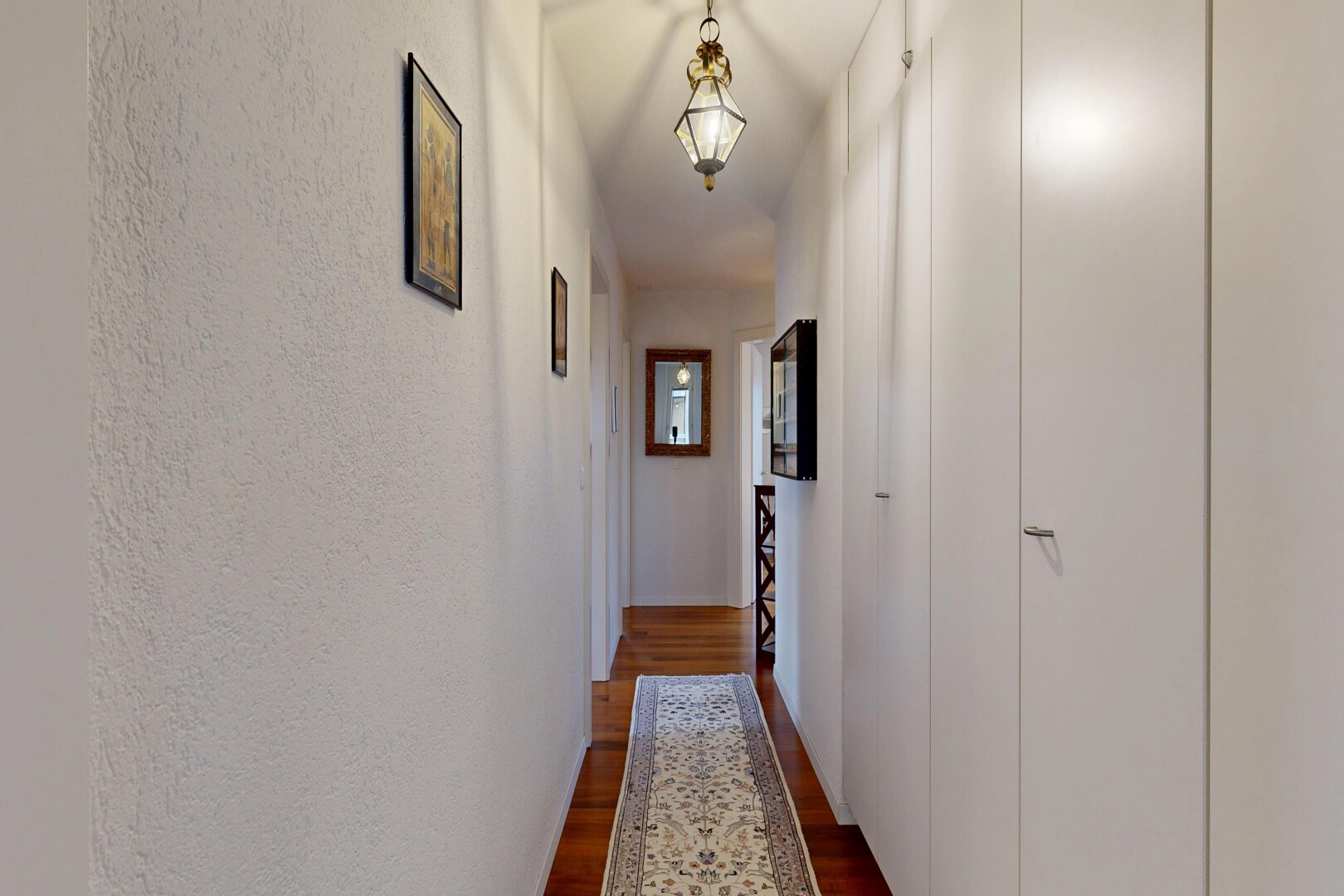 hall with dark wood-type flooring and a textured wall