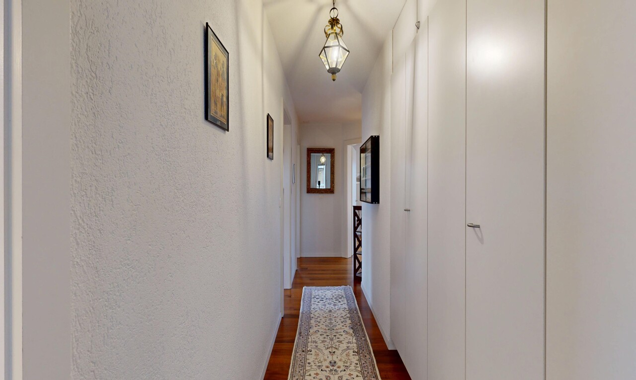 hall with dark wood-type flooring and a textured wall