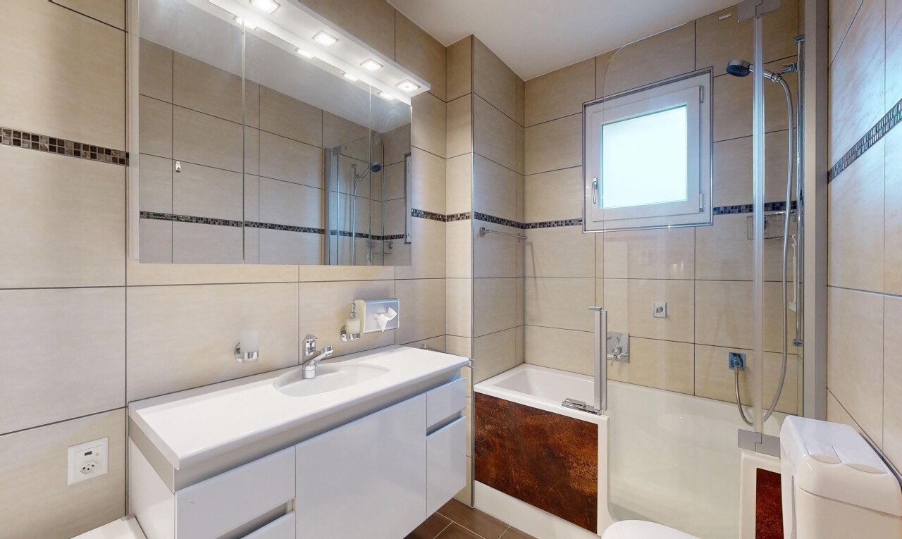 full bath featuring vanity, tile walls, and tiled shower / bath combo