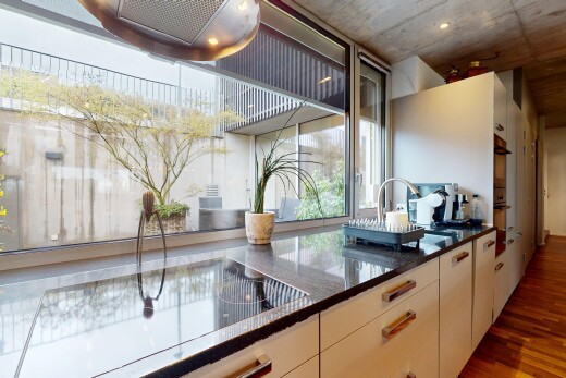 küche mit waschbecken, natürliches licht, stein arbeitsplatten, holzfußboden, und betondecke