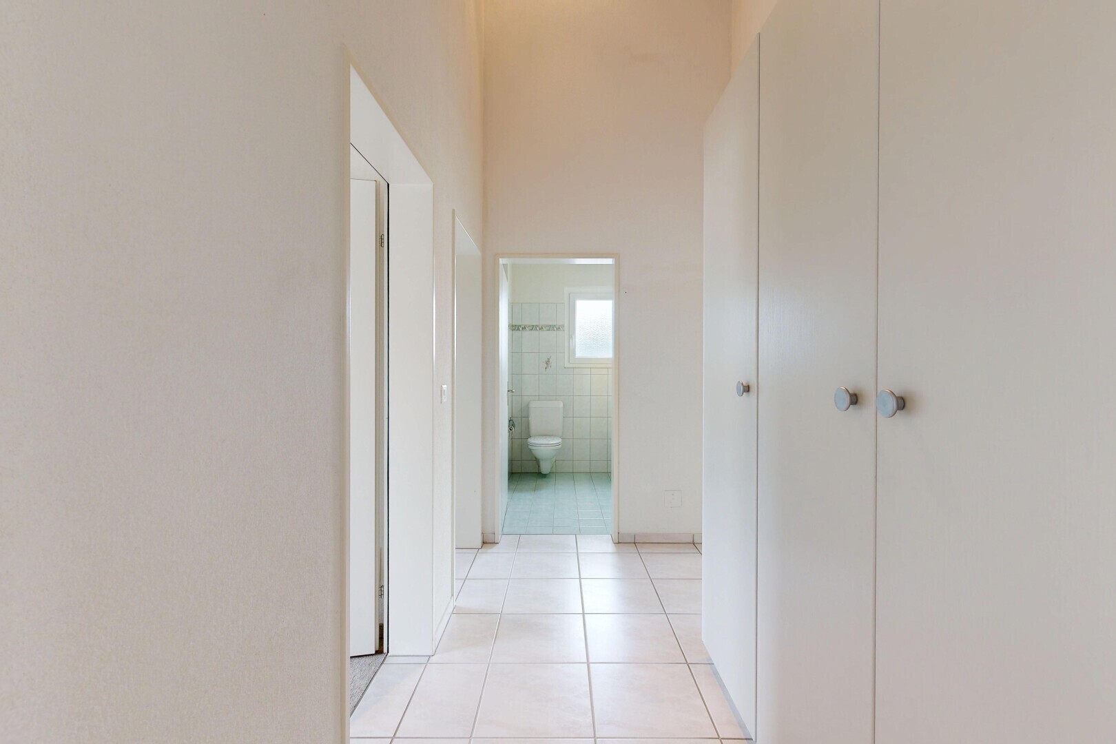 couloir avec light floor, tile floor, sol en carrelage, drywall, et cloison sèche