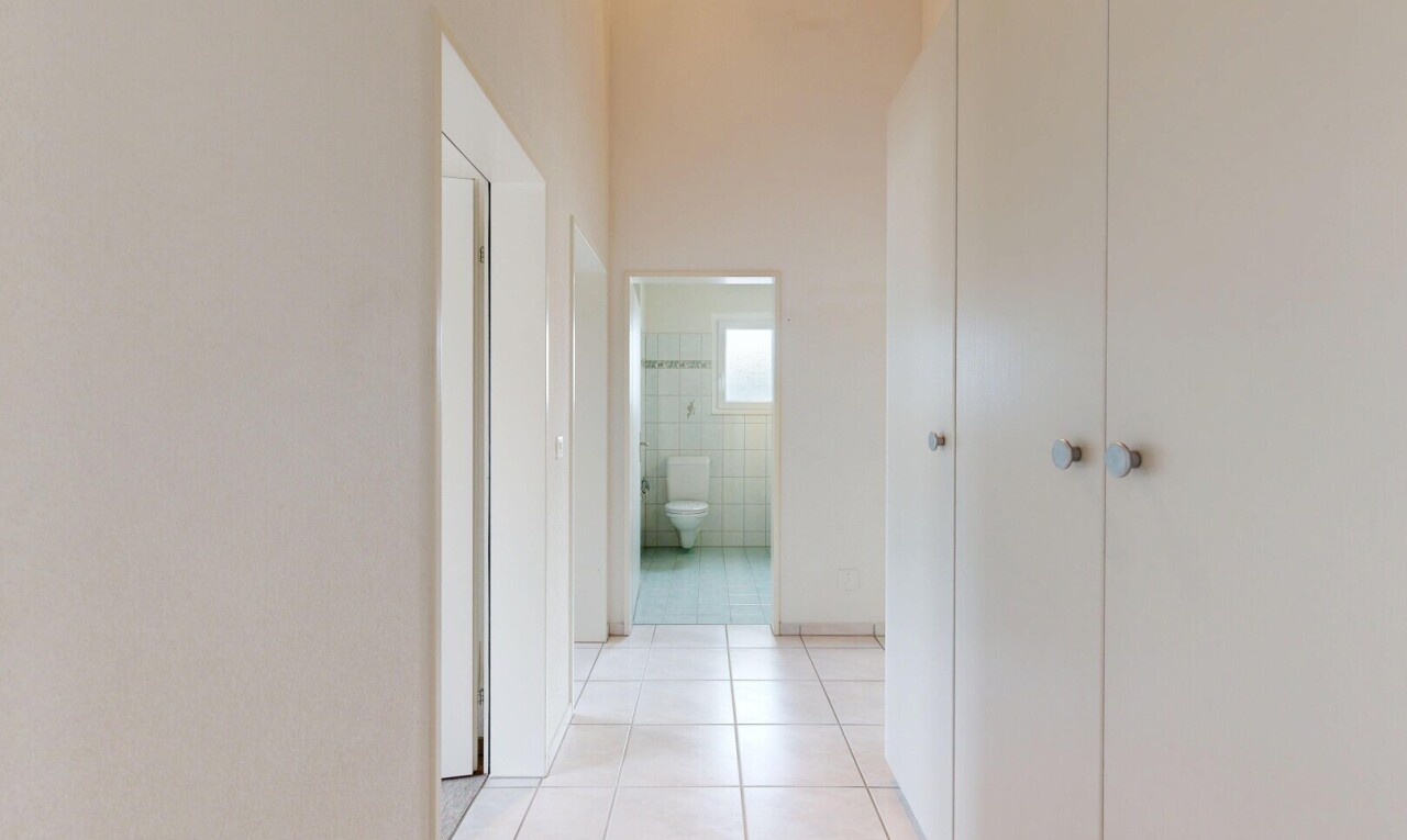 couloir avec light floor, tile floor, sol en carrelage, drywall, et cloison sèche
