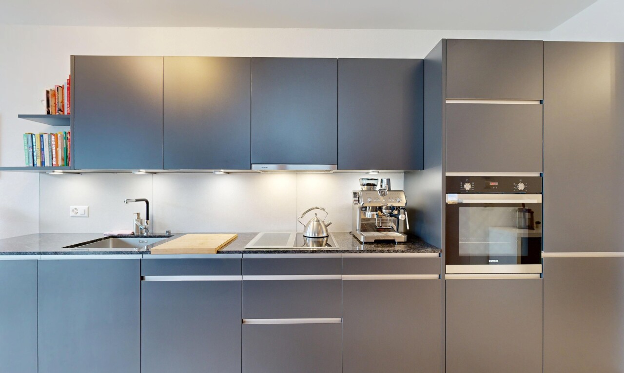 cuisine avec flat panel cabinets, armoires à panneau plat, four, évier, et dark countertops