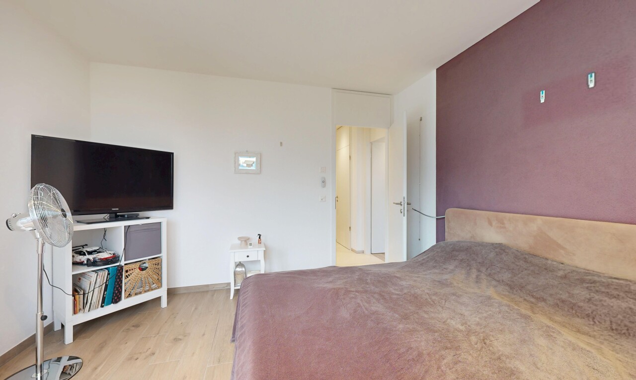 chambre avec télévision, drywall, cloison sèche, wood finish floor, et sol en finition bois