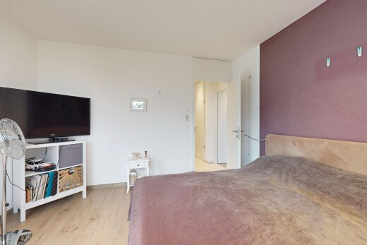 zimmer / schlafzimmer mit fernseher, drywall, gipskartonwand, wood finish floor, und holzfußboden