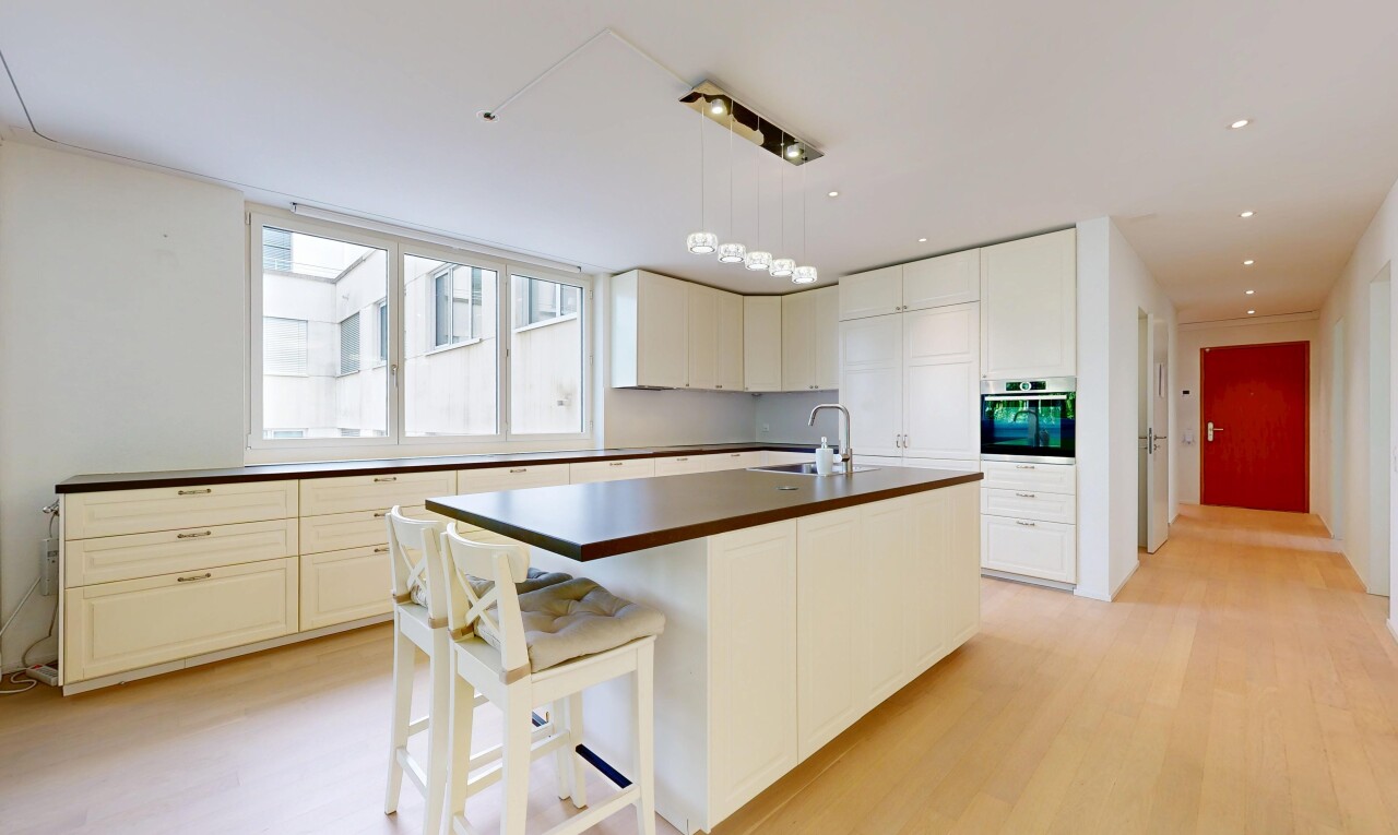 kitchen featuring dark countertops, a kitchen island with sink, stainless steel oven, light wood finished floors, and a breakfast bar area