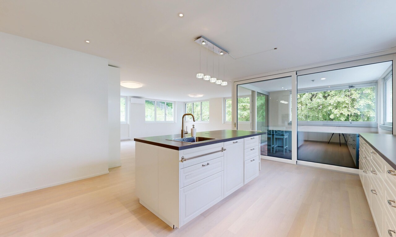 kitchen with an island with sink, light wood-type flooring, pendant lighting, and white cabinets