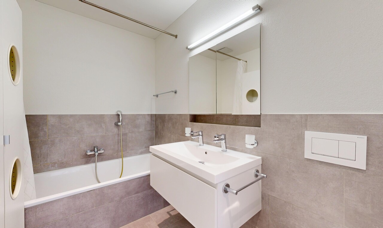 bathroom with a bath, vanity, a tile shower, and tile walls