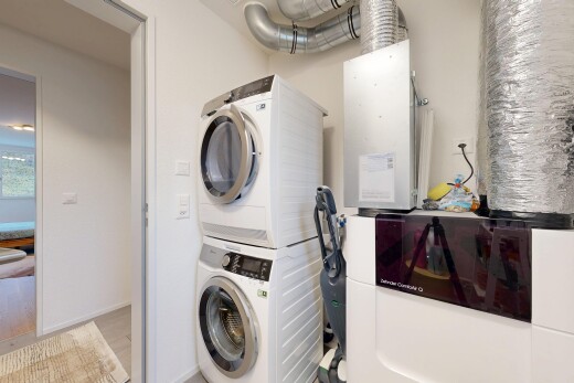 laundry area with stacked washer and dryer and heating unit