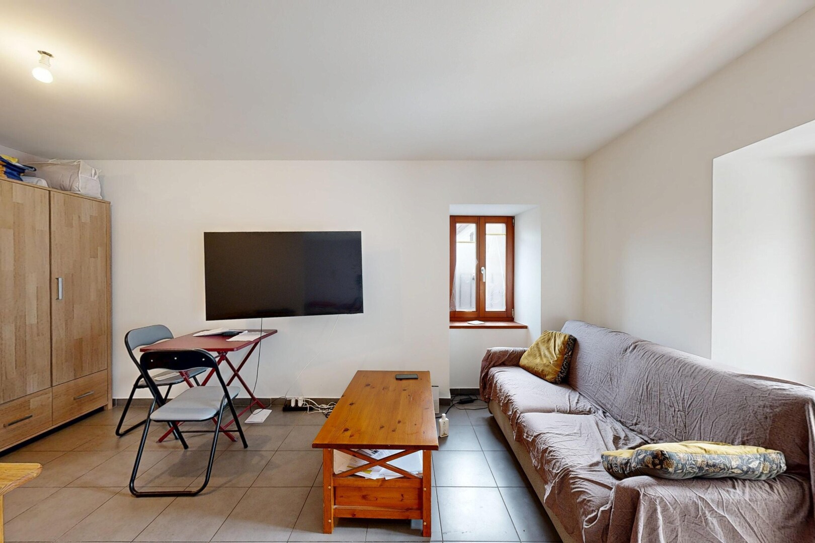 salon avec télévision, cloison sèche, drywall, sol en carrelage, et tile floor