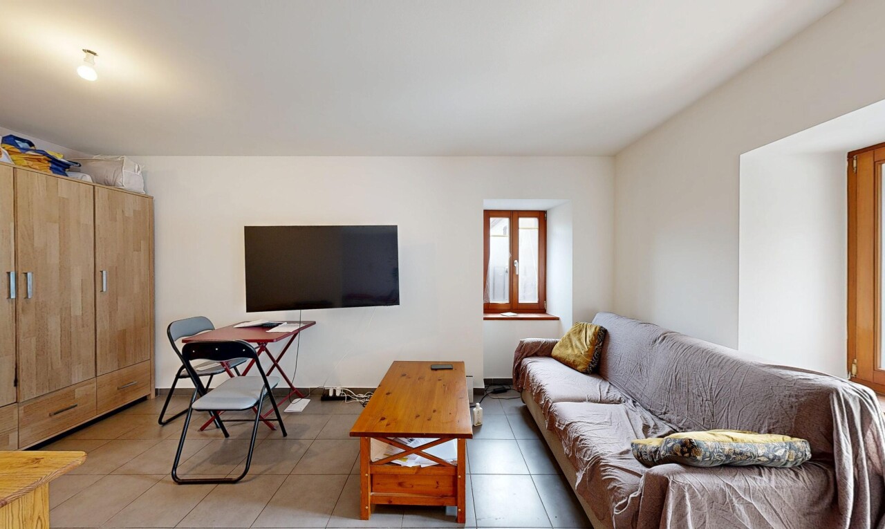 salon avec télévision, cloison sèche, drywall, sol en carrelage, et tile floor