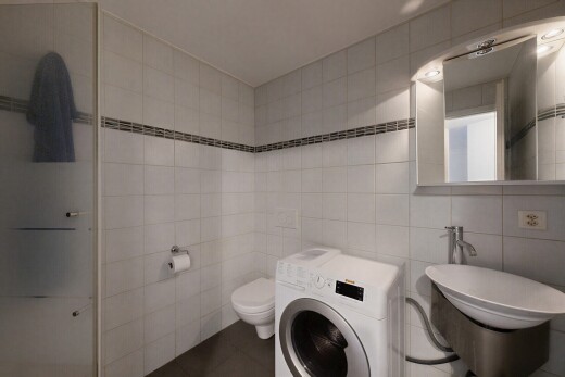 salle de bains avec mur en carrelage, tile wall, lave-linge et sèche-linge, miroir, et inside property