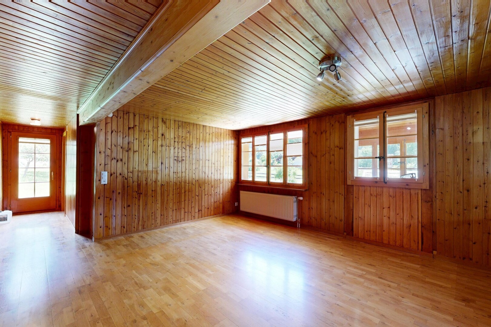 pièce vide avec lumière naturelle, natural light, sol en finition bois, wood finish floor, et radiateur