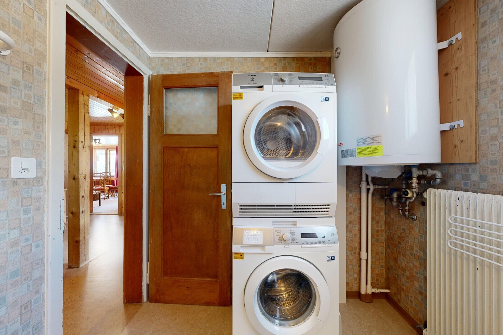 buanderie avec chauffe-eau, light floor, lave-linge et sèche-linge superposés, inside property, et radiateur
