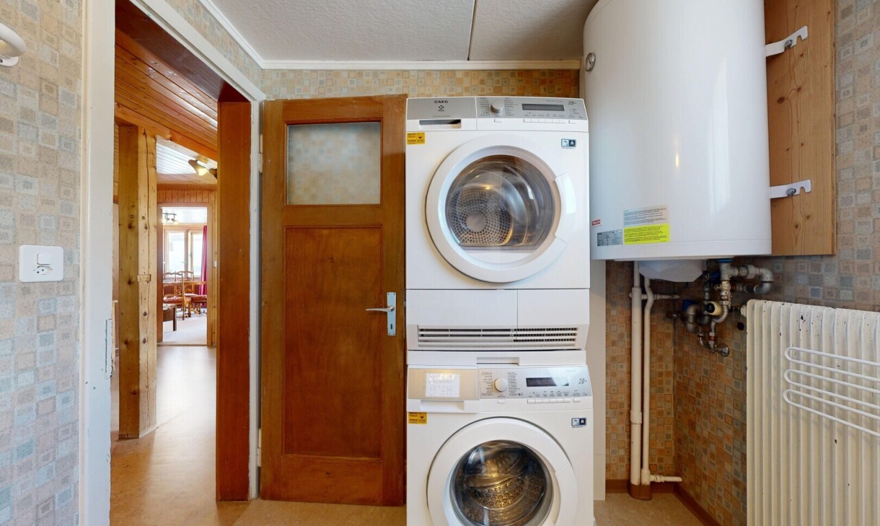 buanderie avec chauffe-eau, light floor, lave-linge et sèche-linge superposés, inside property, et radiateur