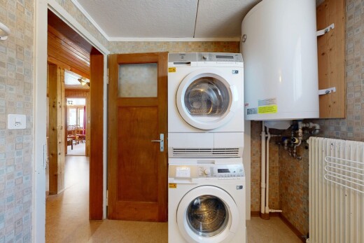 buanderie avec chauffe-eau, light floor, lave-linge et sèche-linge superposés, inside property, et radiateur