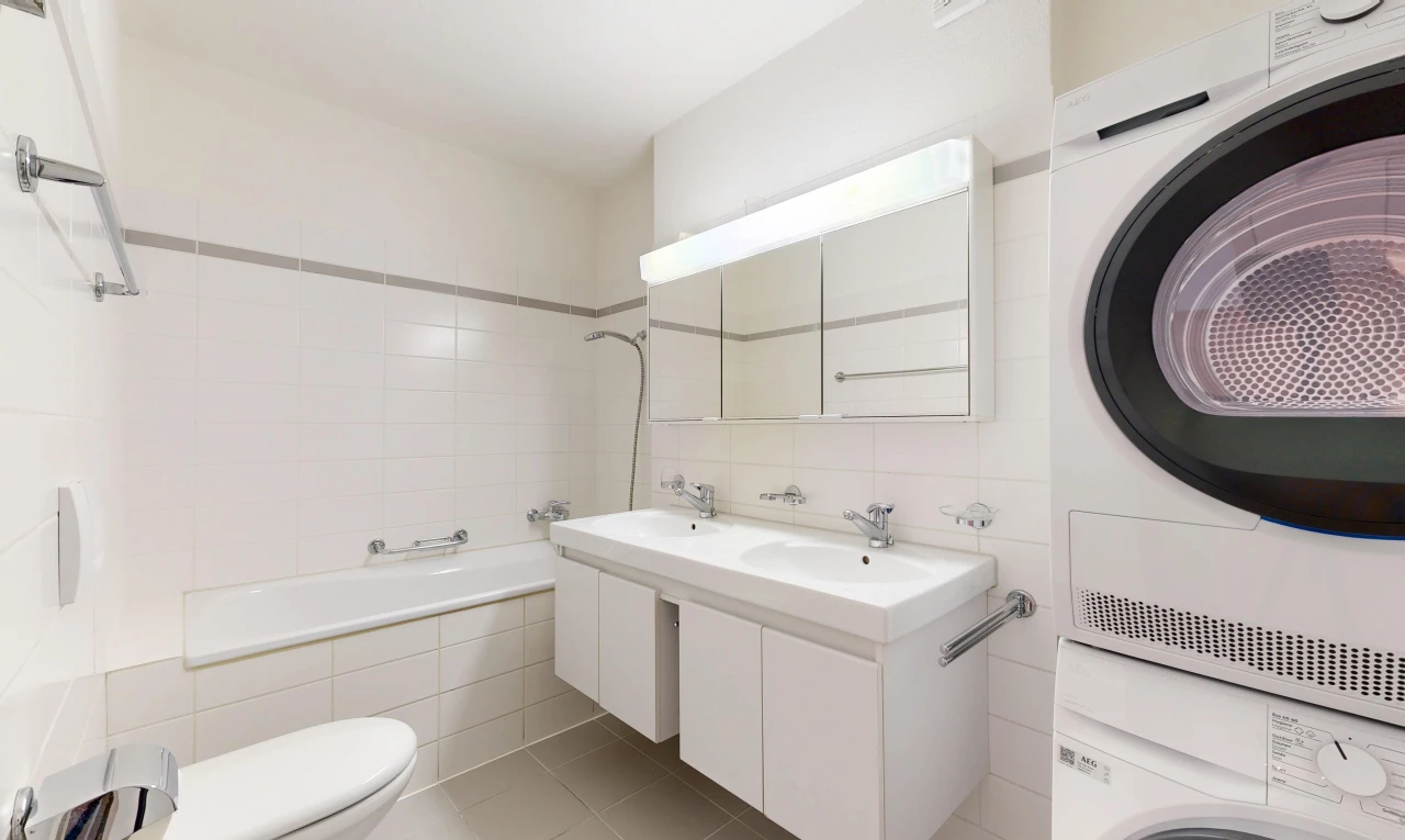 salle de bains avec miroir, salle de bain complète, double vasque, toilette, et lave-linge et sèche-linge superposés