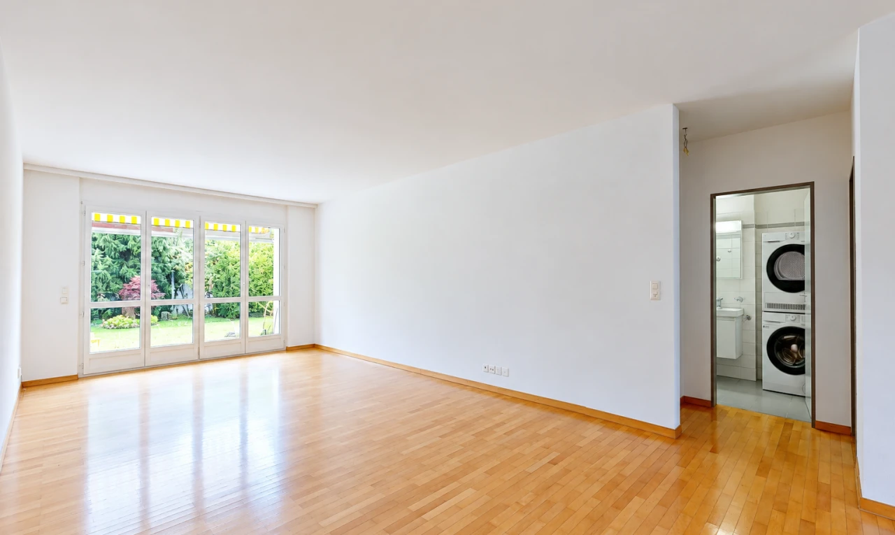 pièce vide avec lave-linge et sèche-linge superposés, cloison sèche, drywall, wood finish floor, et light floor