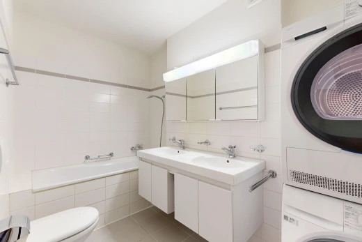 salle de bains avec miroir, salle de bain complète, double vasque, toilette, et lave-linge et sèche-linge superposés