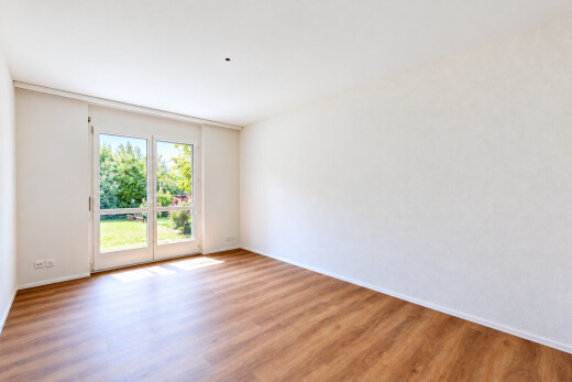 pièce vide avec accès à l'extérieur, cloison sèche, drywall, sol en finition bois, et wood finish floor