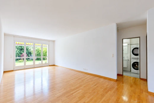 pièce vide avec lave-linge et sèche-linge superposés, cloison sèche, drywall, wood finish floor, et light floor