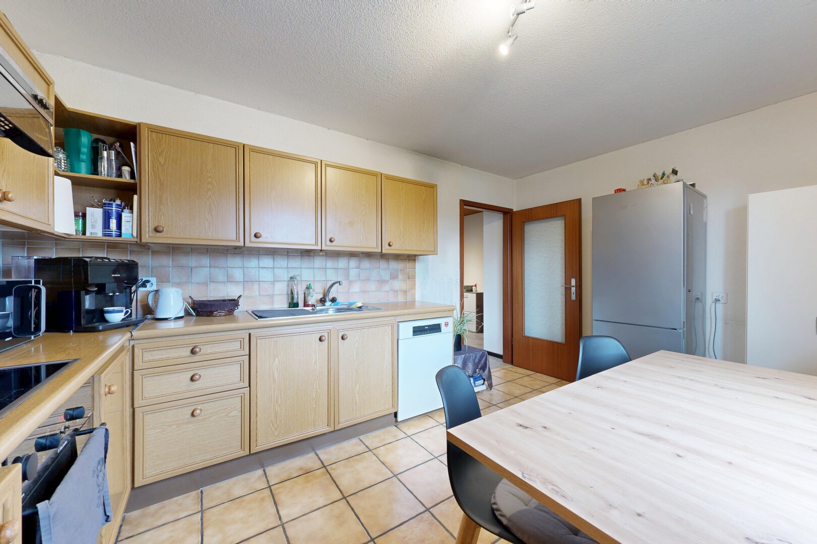 cuisine avec plans de travail, armoires marron clair, réfrigérateur, backsplash, et dosseret