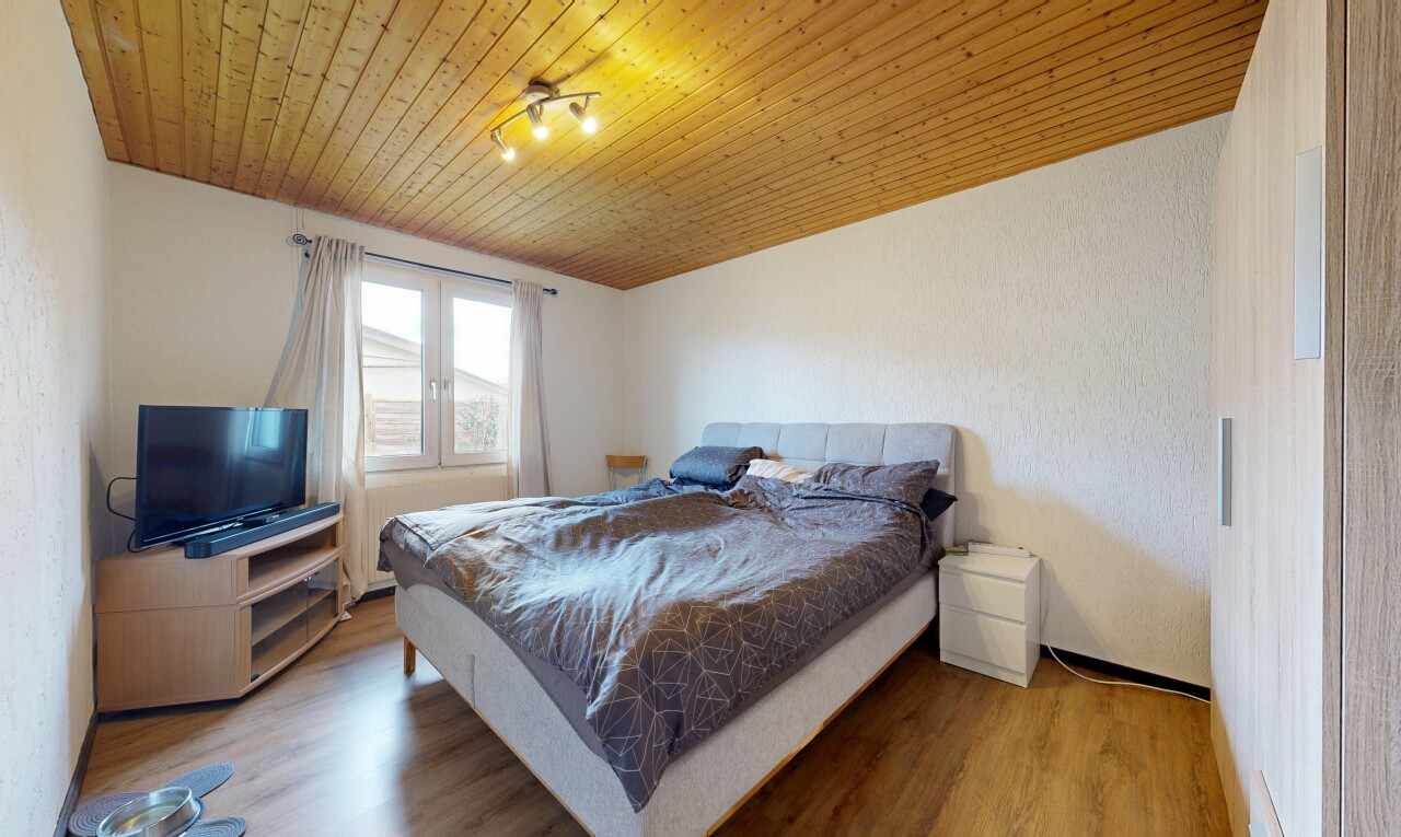 chambre avec wood ceiling, plafond en bois, télévision, wood finish floor, et sol en finition bois
