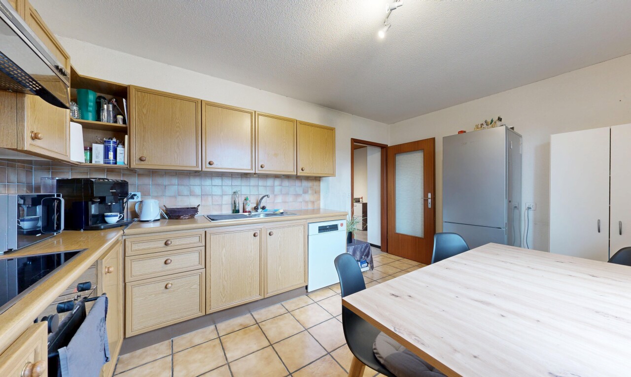 cuisine avec plans de travail, armoires marron clair, réfrigérateur, backsplash, et dosseret