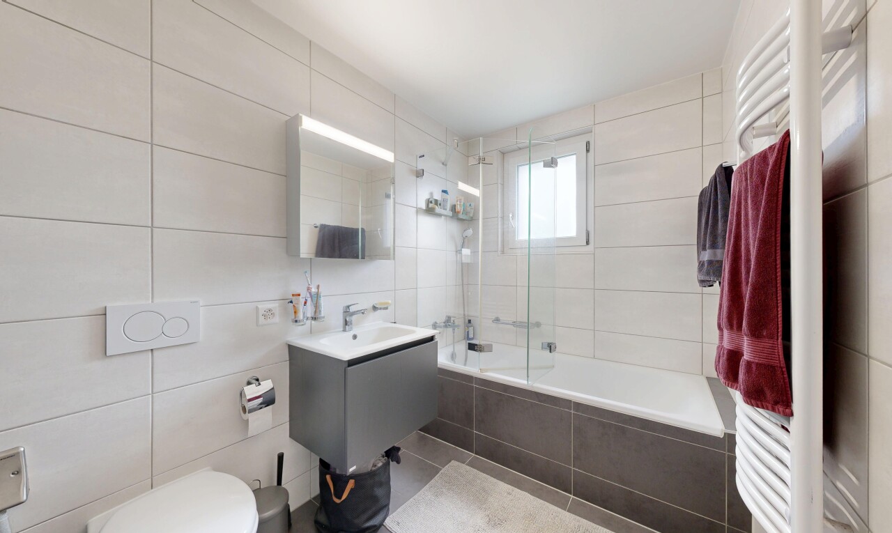 full bathroom with tile walls, tiled shower / bath combo, a towel warming rack, and vanity