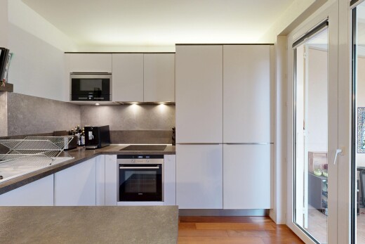 cuisine avec four, micro-ondes, armoires blanches, inside property, et sol en finition bois