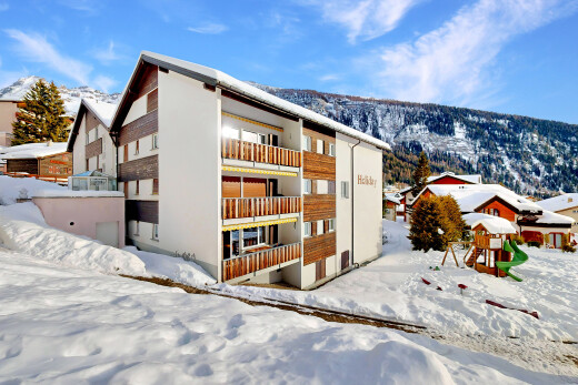 snow covered property featuring a mountain view and a view of apartment building / complex