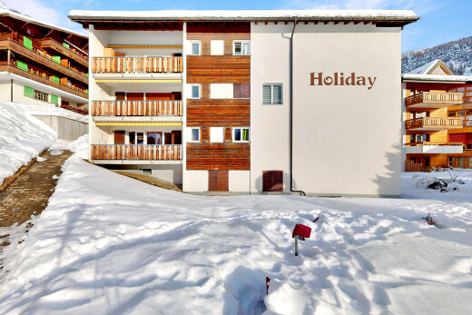 snow covered building featuring a view of apartment building / complex