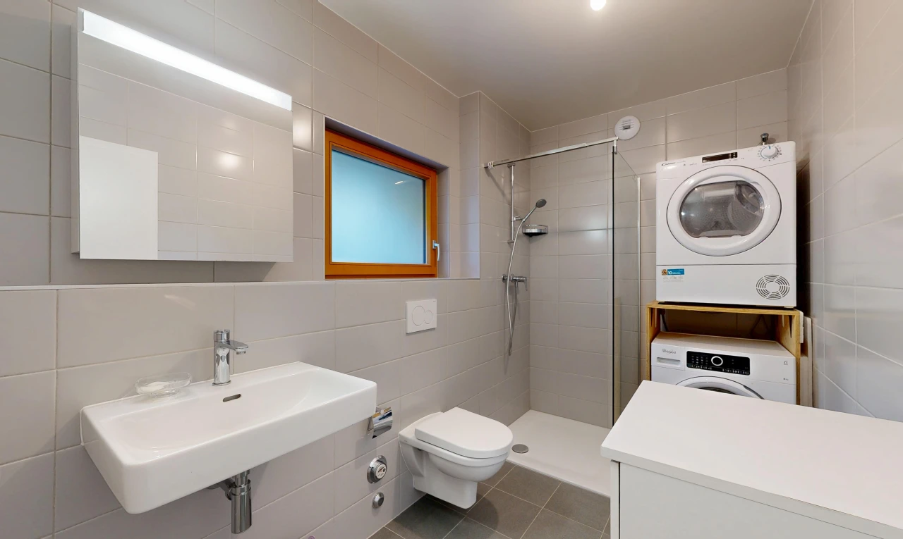 salle de bains avec tile wall, mur en carrelage, salle de bain complète, douche, et lave-linge et sèche-linge superposés