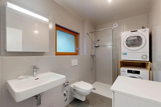 salle de bains avec tile wall, mur en carrelage, salle de bain complète, douche, et lave-linge et sèche-linge superposés