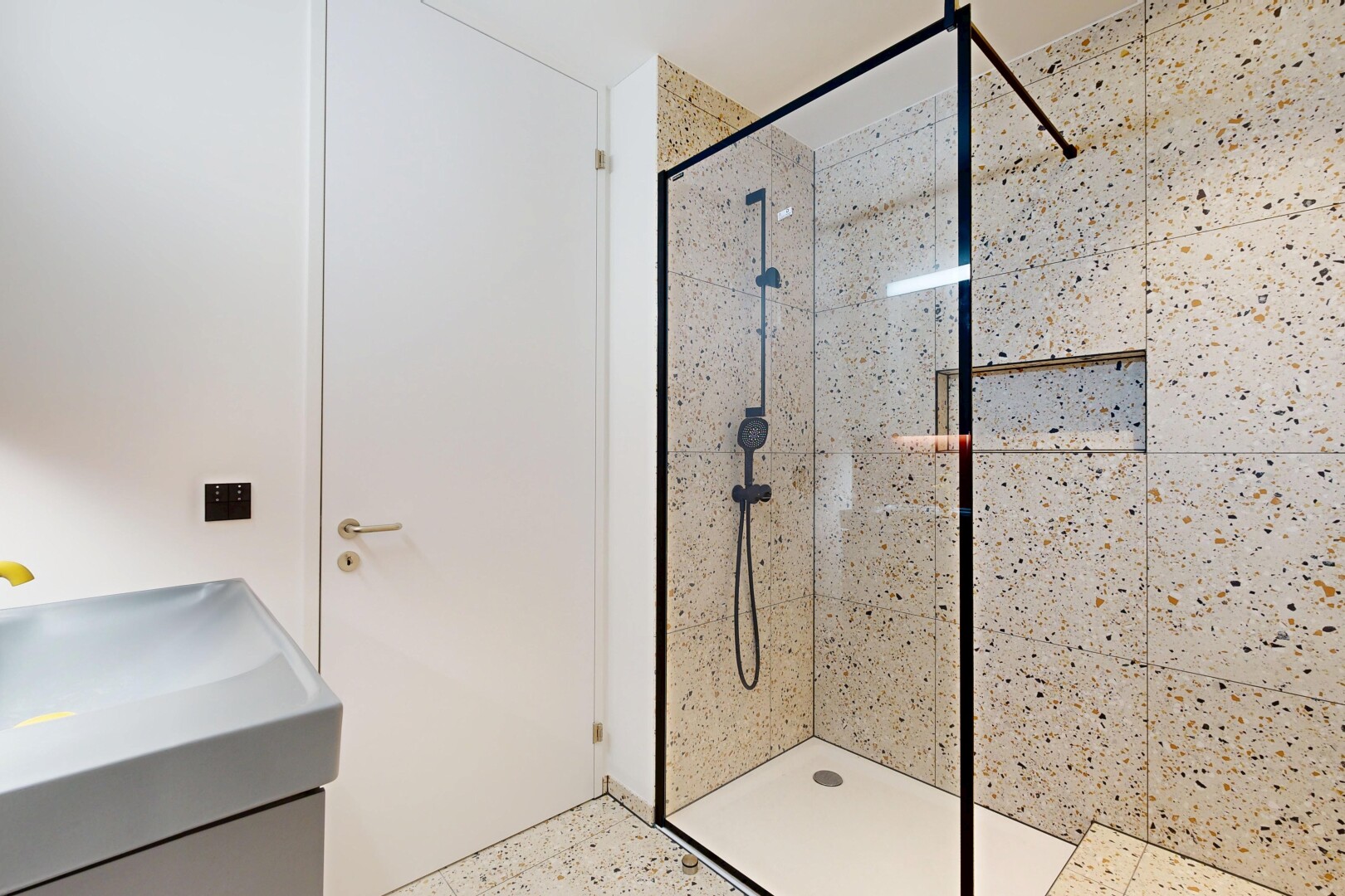 full bathroom with a tile shower, speckled floor, and vanity