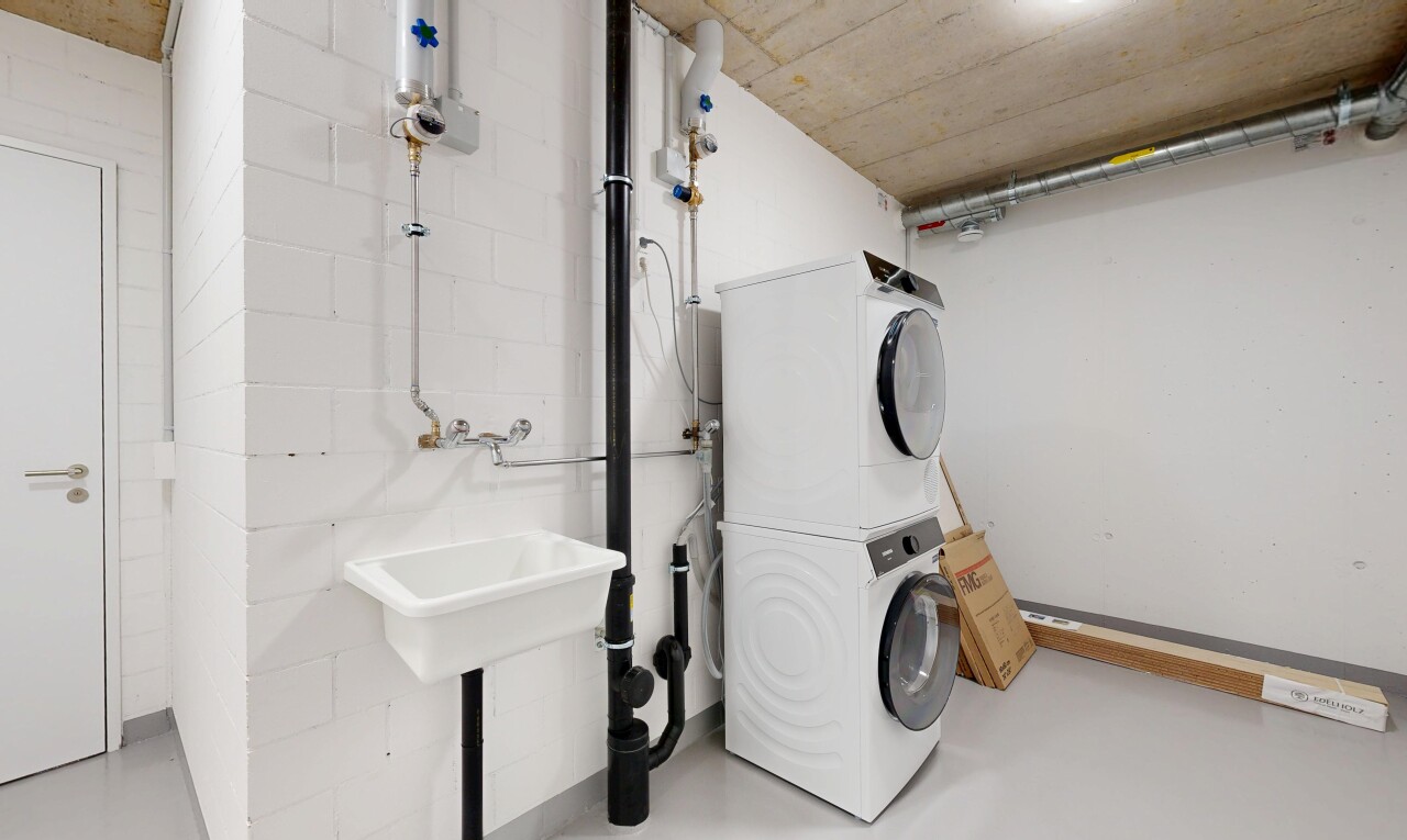 laundry area featuring stacked washer / drying machine and finished concrete floors
