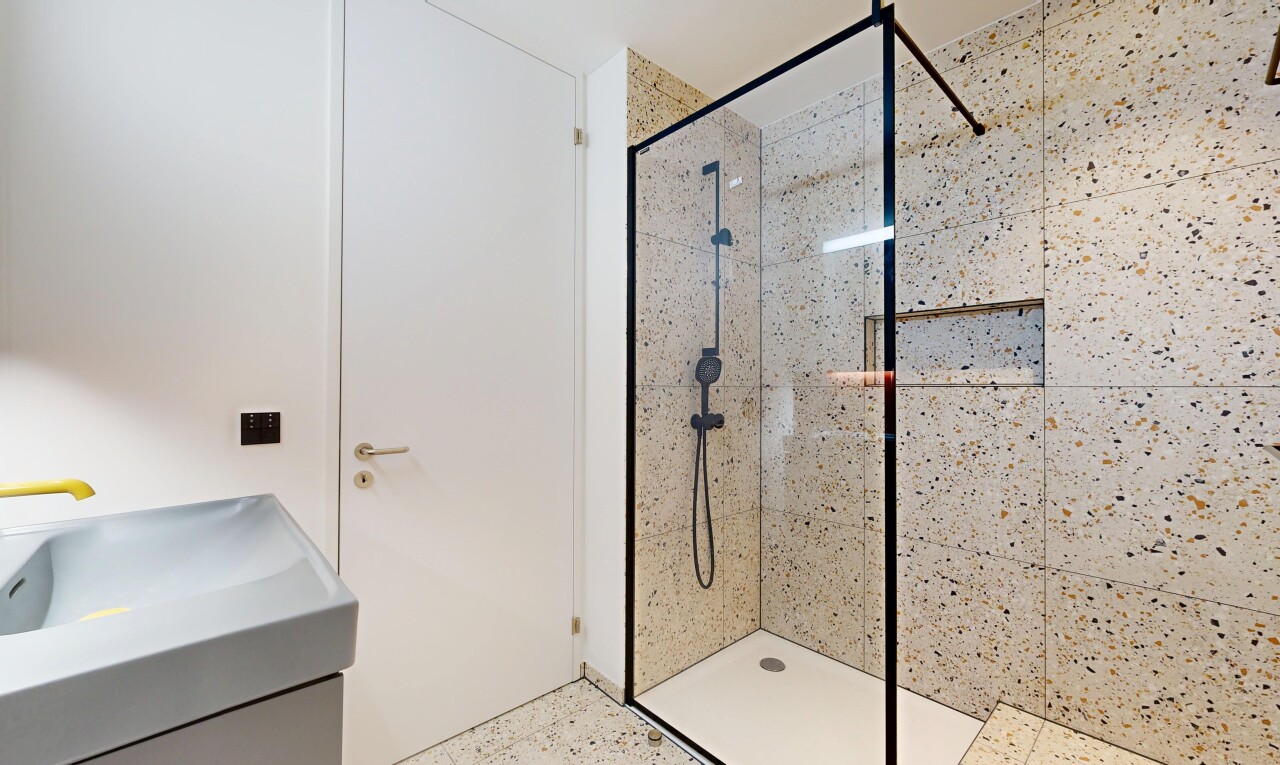 full bathroom with a tile shower, speckled floor, and vanity