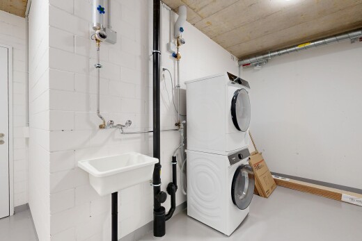 laundry area featuring stacked washer / drying machine and finished concrete floors