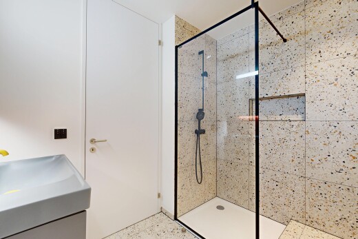 full bathroom with a tile shower, speckled floor, and vanity